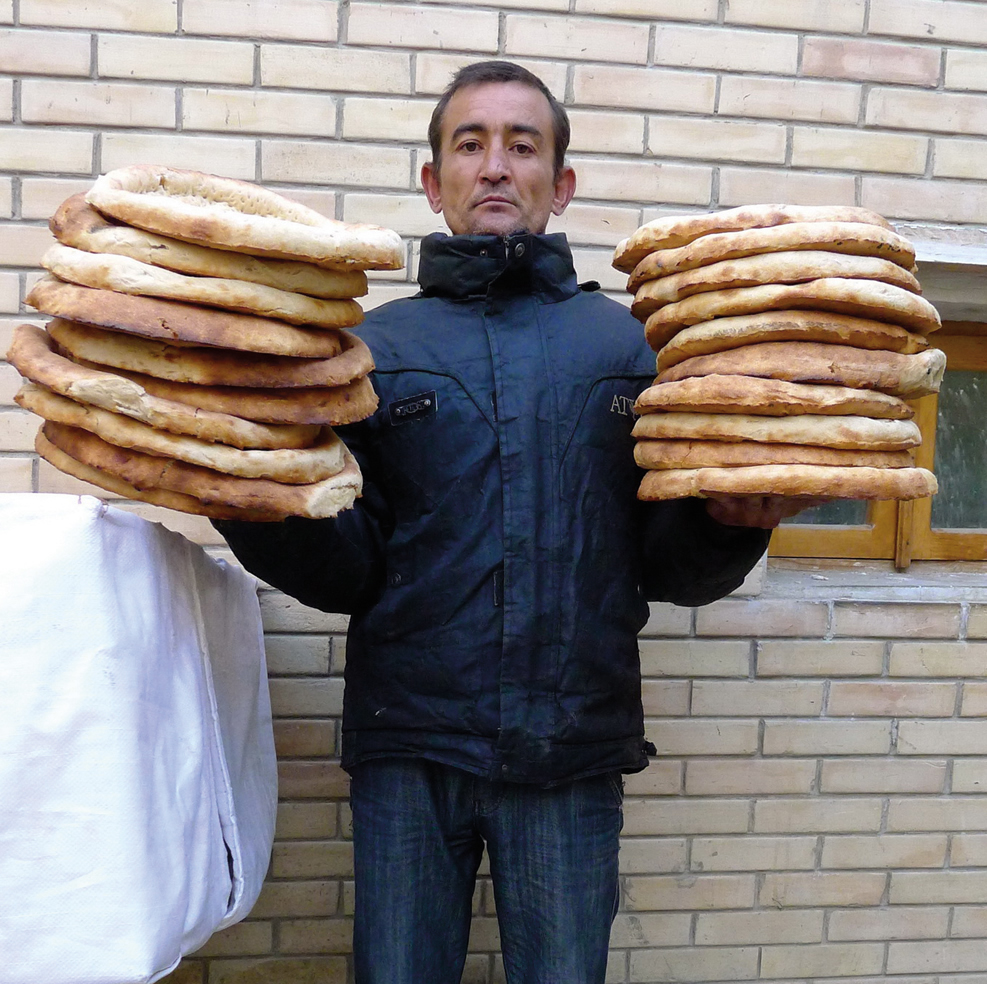 Timor, a deliveryman in Bukhara, holds non that he will carry to customers by bicycle.
