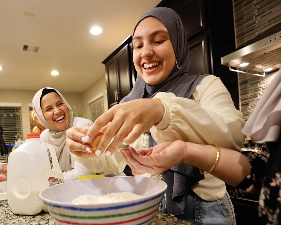 Eveliz Gutierrez, left, supervises as her niece Jaliliah Fletcher works the dough to make buñuelos, traditional Colombian fried pastry balls, at a family gathering.