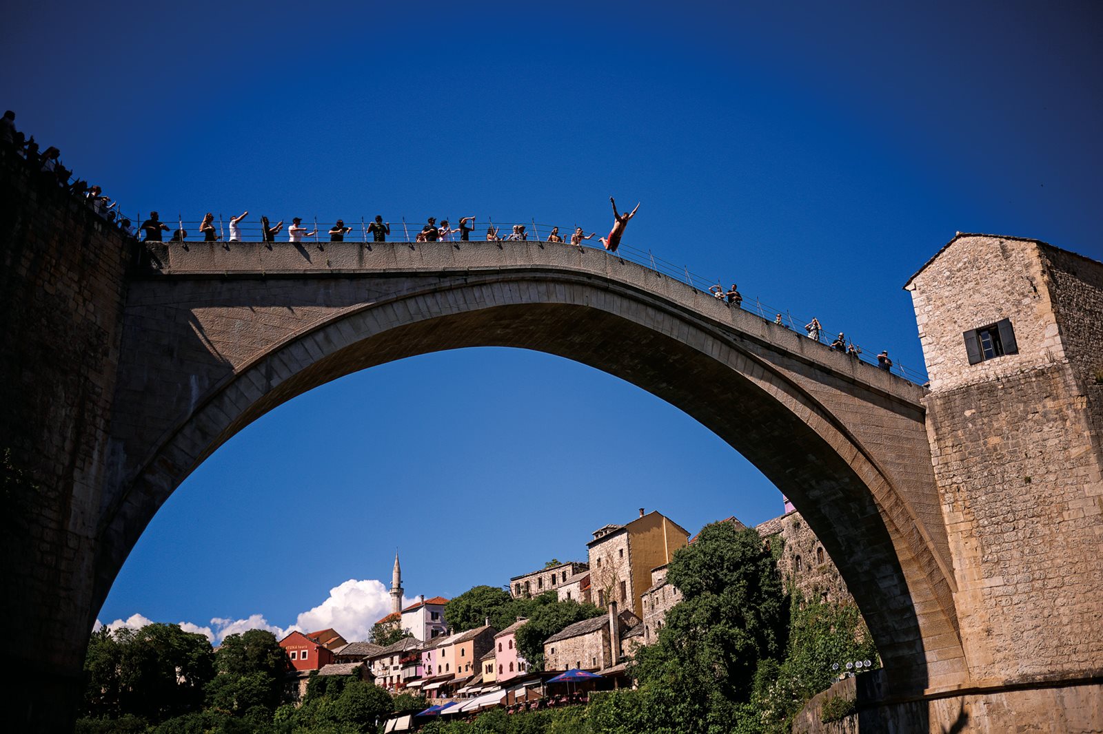 Tourists watch a diver leap into the river Neretva from the bridge, which draws large crowds year-round.