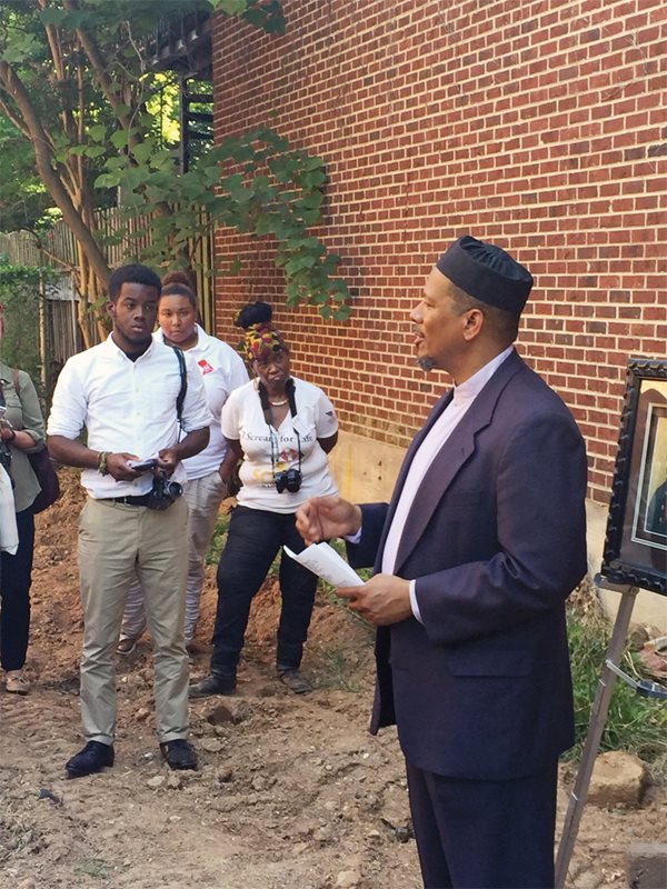 <p>Taib Shareef, imam at Masjid Muhammad in Washington, D.C., offers <em>salat al-janazah&mdash;</em>the traditional Muslim funeral prayer&mdash;for Yarrow Mamout on the site of his former home at Dent Place. Mamout was said to have been buried in the corner of the garden where he &quot;resorted to pray&rdquo; at the time of his death in 1823.</p>
